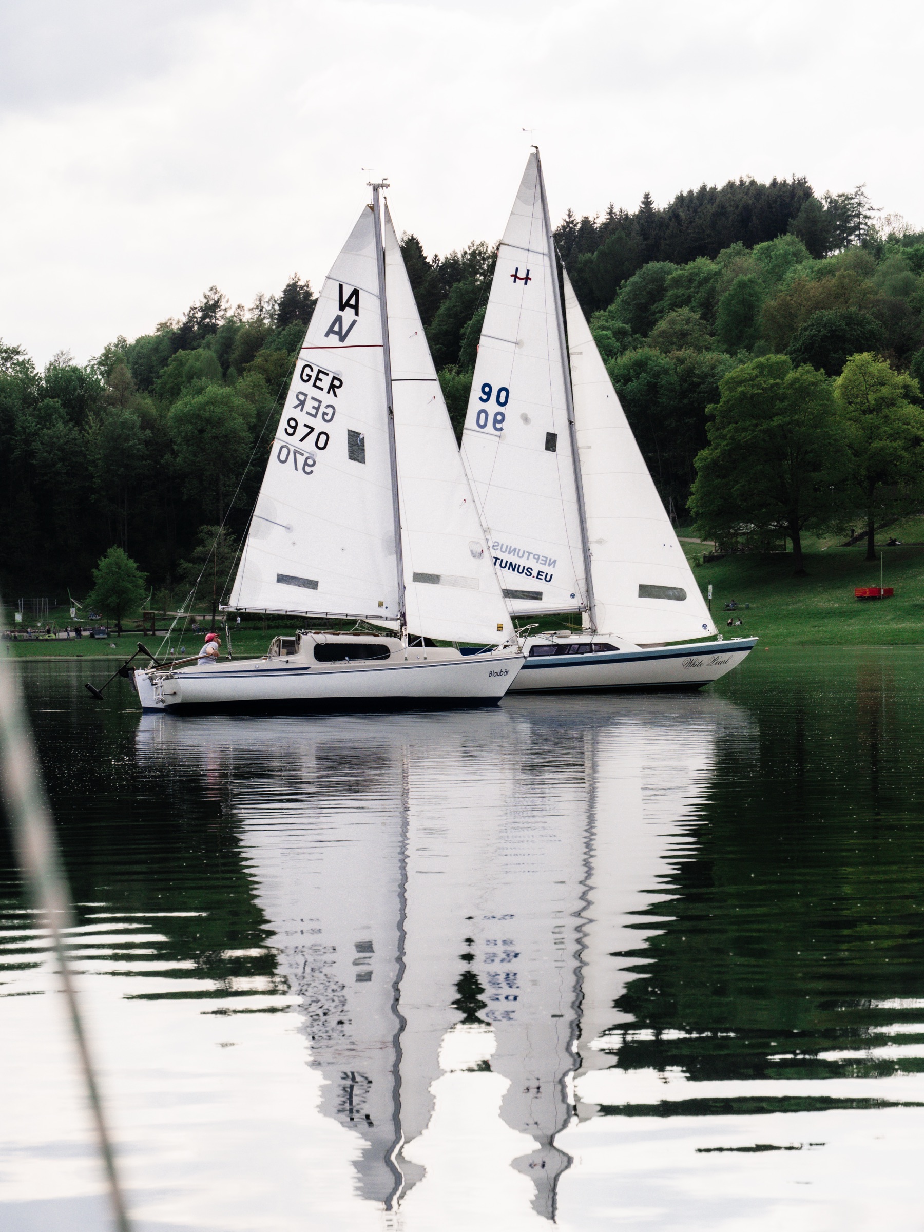 Zwei Segelboote spiegeln sich im glatten Wasser